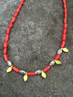 Ketting van rood koraal en lieveheersbeestjes op blaadjes